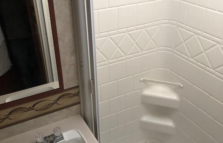 Spacious bathroom with shower, sink, toilet and extra cabinets for storage.