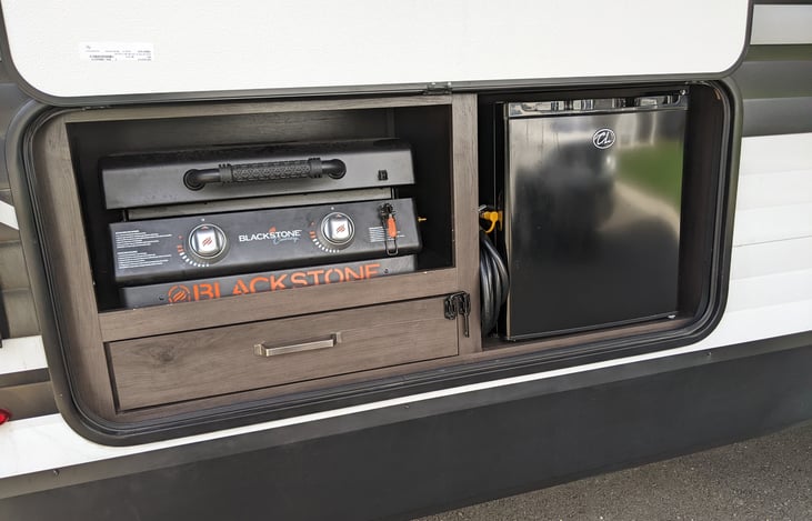 Outdoor kitchen is the storage area for the blackstone griddle.  There is also a 12 foot propane hose to connect to the rv's propane system.  This fridge can be used when the Rv is connected to power.