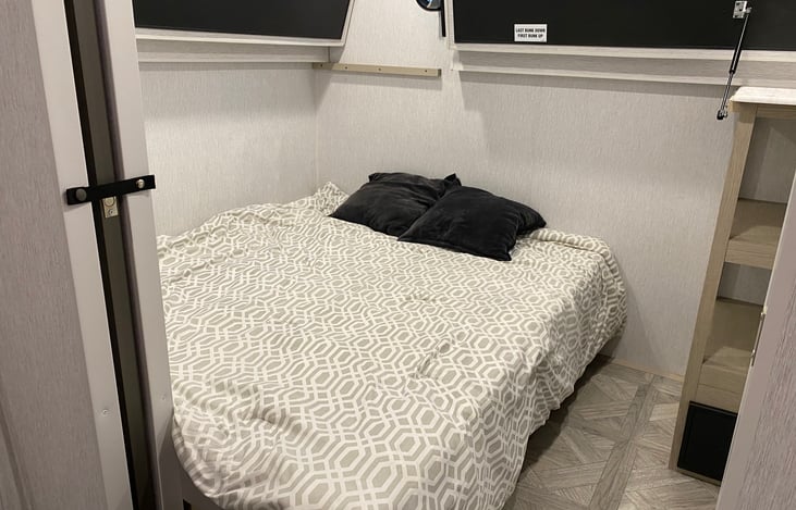 Bunk room with both bunks in the upright position and the Versa Queen open.  Linens for the Versa Queen are in tubs stored under the sofa.