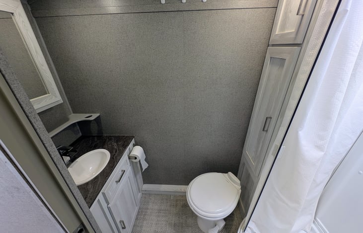 Convenient bathroom with ample storage, toilet and shower.