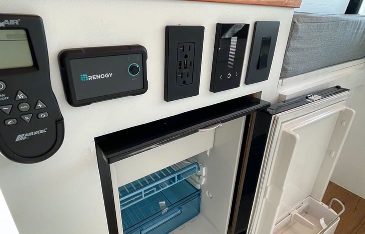 Multiple outlets and plugs, heater controls, automatic light dimmer, power on/off switch. Dometic brand front access fridge.