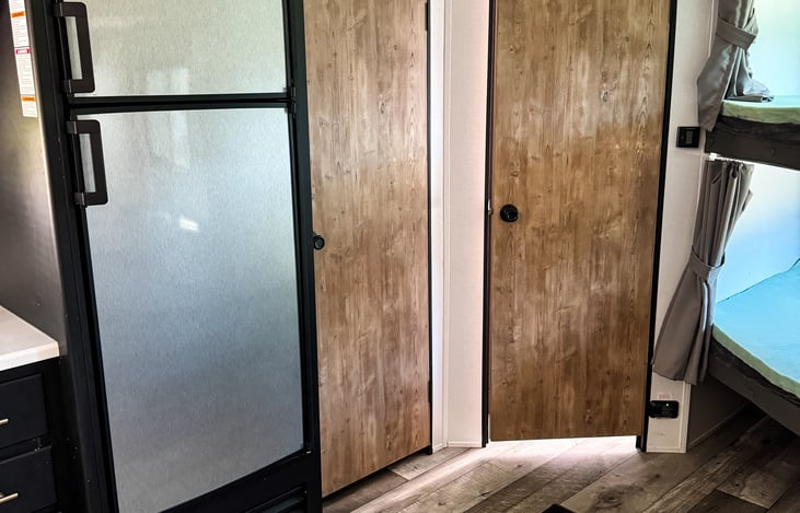 Looking at the Fridge, Pantry, and Bathroom from the couch and table