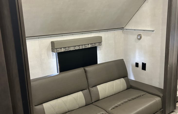 Bunk area with top bunk raised. Creates entertainment seating area with TV access.