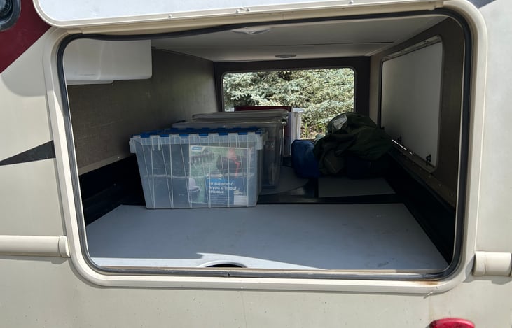 Generous storage including camping chairs, portable propane grill, cooler, folding table, hoses, water filter, mosquito repellent, and more!