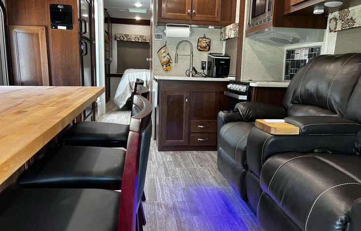 View of the living room/dining area and kitchen from the front cab area of the motorhome.