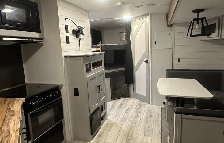 Oven, 2-burner gas cooktop, microwave and main living/dining area. (Shown without TV, but TV is installed)