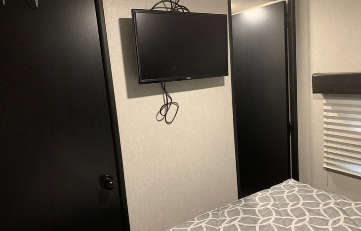 The master bedroom has closet space and overhead cabinets on both sides of the bed. It also has its own tv.