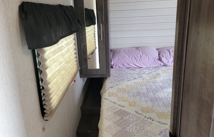 Front master bedroom with night stands, usb, and charging outlets, overhead, and closet storage on each side. Sliding doors for privacy.