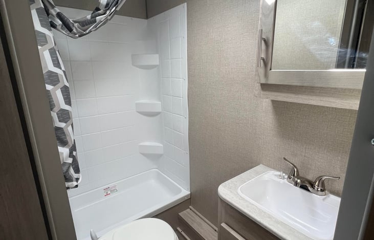 Spacious bathroom with a shower, toilet, sink, and more storage.