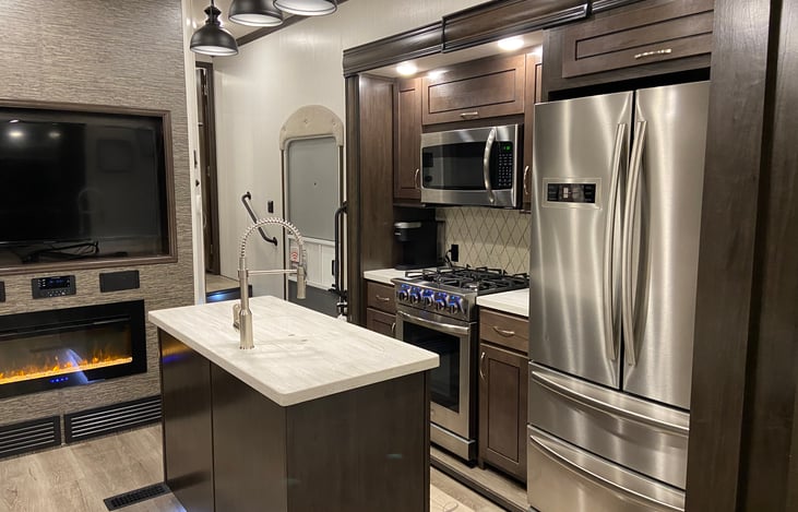 Kitchen with residential fridge, gas oven microwave , coffee pot, Keurig, toaster, essential dinnerware, pots, pans as well as dish and hand towels.