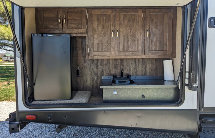 Outdoor kitchen, complete with fridge, sink, griddle, and cook top.