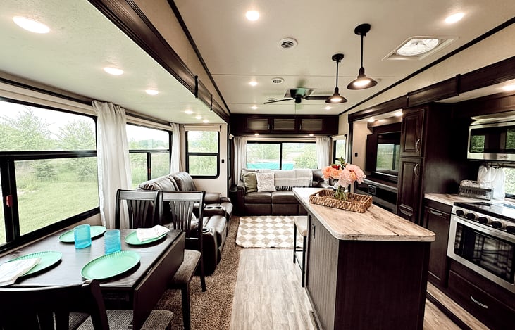 Large living area includes a table & four chairs, reclining theatre seats with heat & massage, and a comfy couch that converts into a queen-sized bed.  Everything has been updated with cute decor.