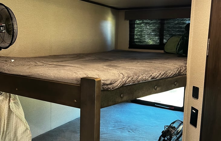 Top bunk. Mattress shown without bedding. Curtain for privacy. Wall mounted fan included.