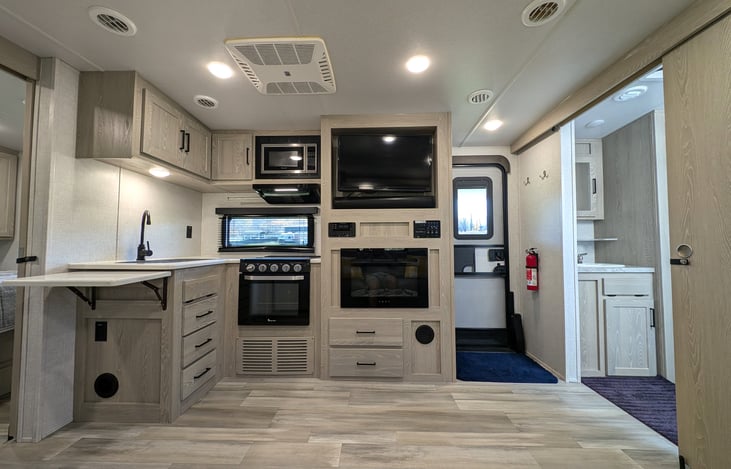 Flat screen TV over faux fireplace, stove, oven, microwave