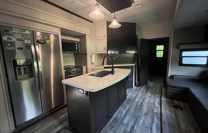 Kitchen with residential refrigerator, propane stove range, oven, microwave and convection, and large sink.
