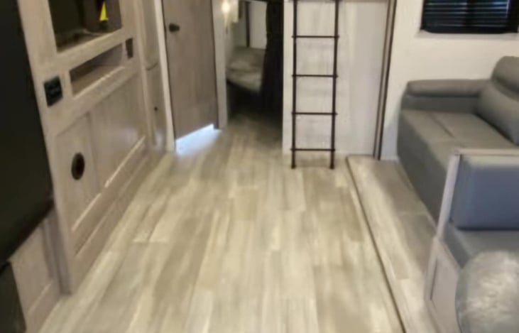 Living area with TV. Double bunks adjacent to living area and bathroom in rear of trailer.