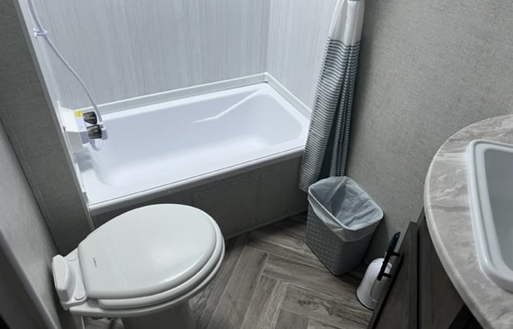 Bathroom with shower/tub combo, toilet, sink, and mirrored medicine cabinet. Bathroom has vent, fan, light switch, and towel rack.
