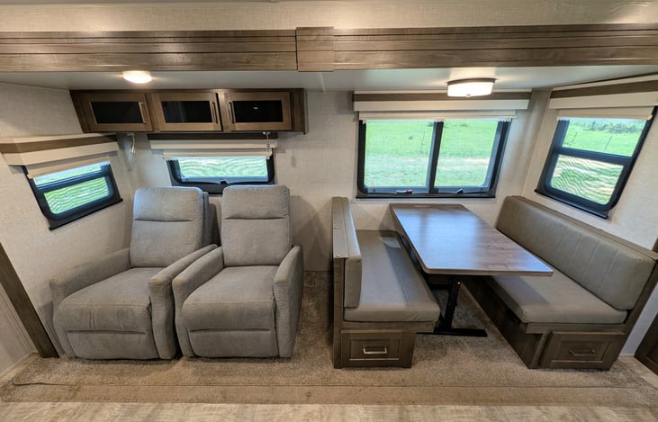 Spacious open-concept living area w/ dual recliners, TV & fireplace. Full kitchen features a residential fridge, 3-burner stove, oven, microwave, deep sink & booth dinette! Natural light throughout.