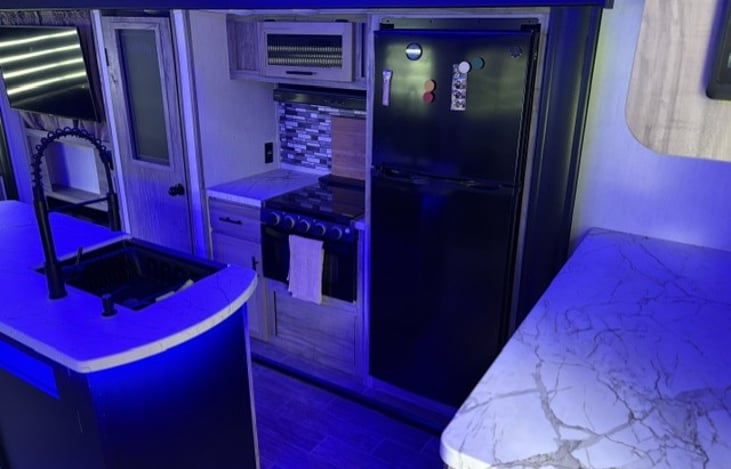 kitchen area, stove, fridge/freezer, and counter top area. Pantry door is to the left of the stove.
