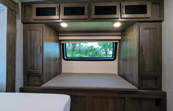 Private front bedroom features a walk-around Queen bed, TV, ample wardrobe storage, and a cozy built-in window seat nook—perfect for relaxing with a book! Full of natural light from 6 windows.
