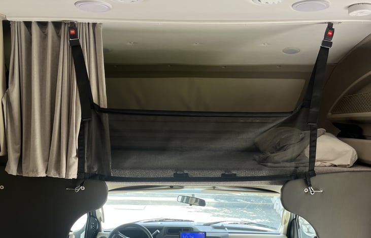Overhead bunk with safety panel and privacy curtain.