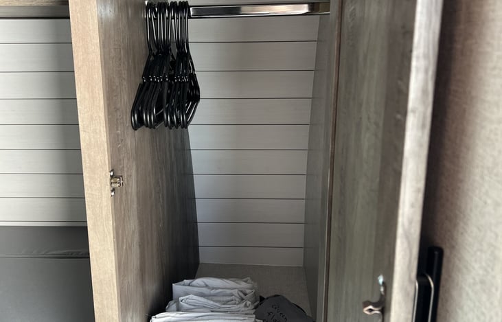 Wardrobe storage with rod and hangers. Queen size linens for both beds and both bunks.
