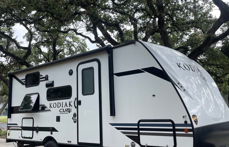 Exterior of camper. Through and through storage on the front of the camper. Camper exterior also includes awning w lights, outdoor fridge and grill.