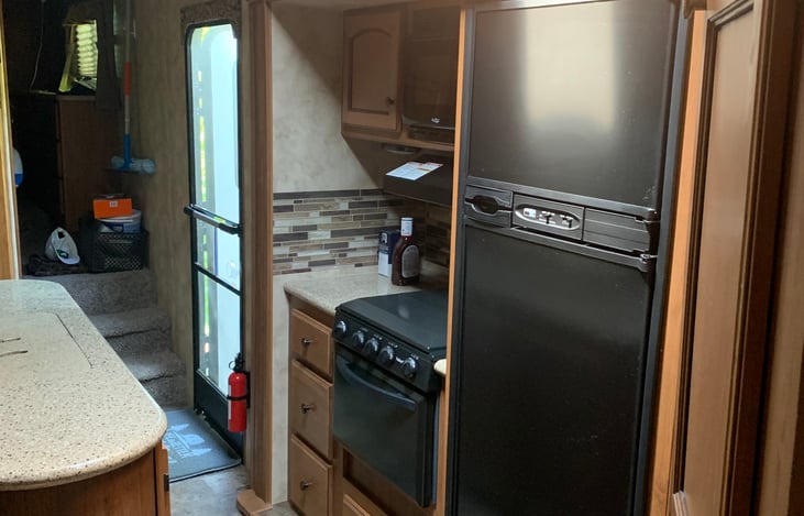 Kitchen with stovetop and fridge/freezer.