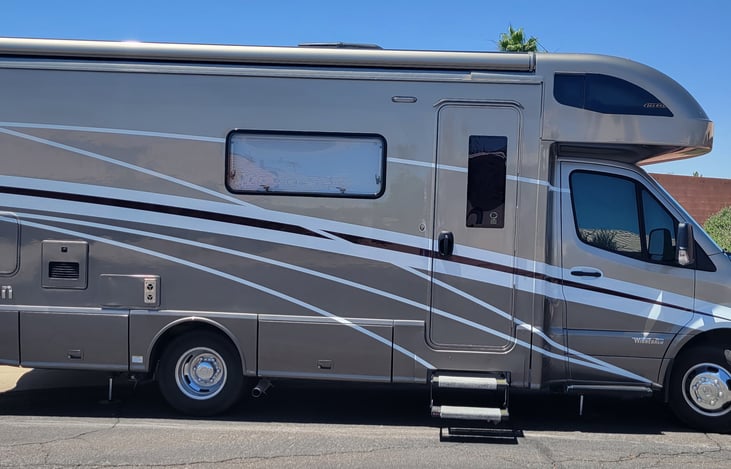 Entry door with access steps down, note storage.  Full length awning and openable windows.