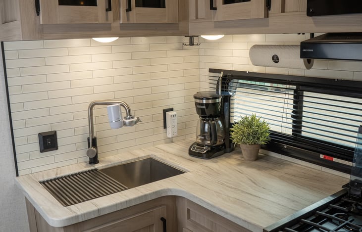 fully equipped kitchen with large single basin sink, coffee maker, 3 burner stove, full sized fridge and freezer, oven, and microwave