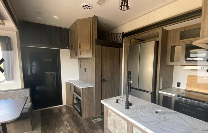 The kitchen holds 2 slides which open for ample space. A full sized fridge, stove, and sink with cover for extra prep space. The pantry has plenty of room for a weekend getaway. Cabinets are stocked!