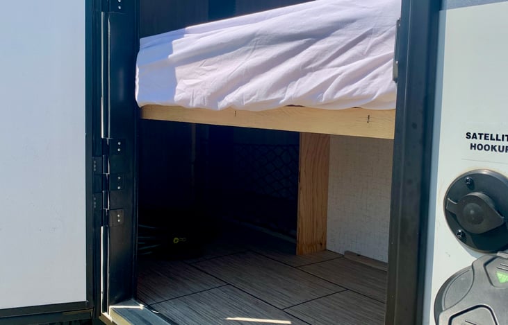Lower bunk bed folds up and exterior door allows for extra storage during travel.