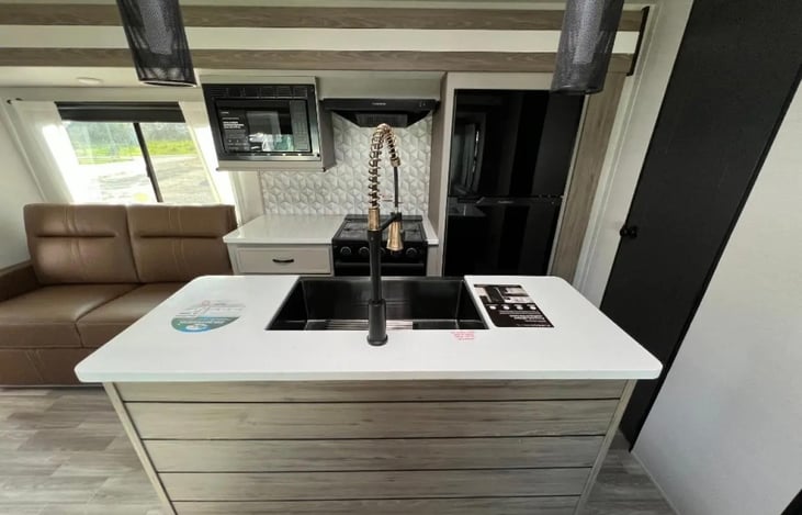 Kitchen with island, microwave, oven with 4 burner stovetop and large refrigerator