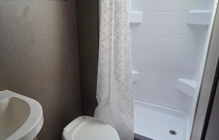 Rear bathroom with shower curtain, toilet, and sink.