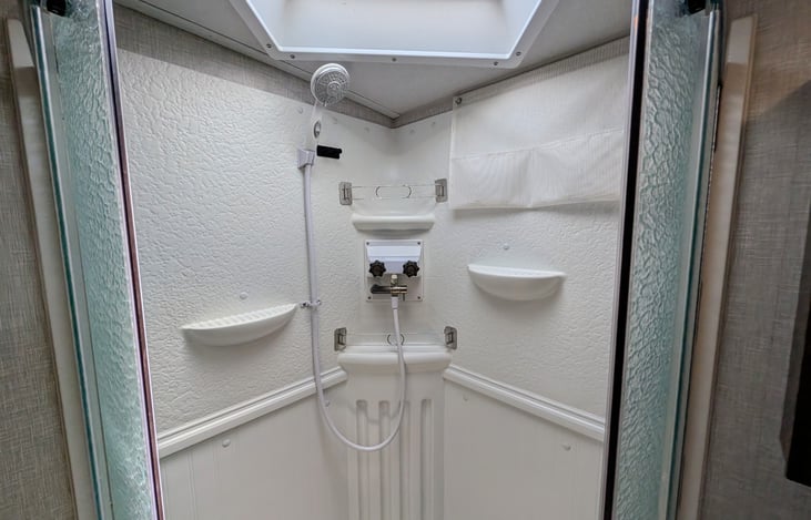 Spacious bathroom with large corner shower, glass door, and skylight for extra headroom! Includes a porcelain foot-flush toilet, medicine cabinet, vanity, and plenty of towel storage + washer/dryer.