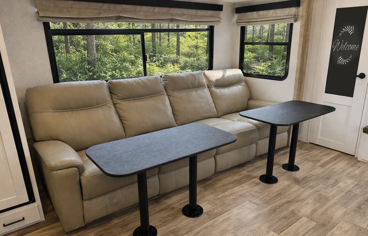 Rear living area featuring four reclining theater seats with plush cushioning and panoramic windows. Perfect for relaxing, movie nights, or unwinding after a day outdoors.