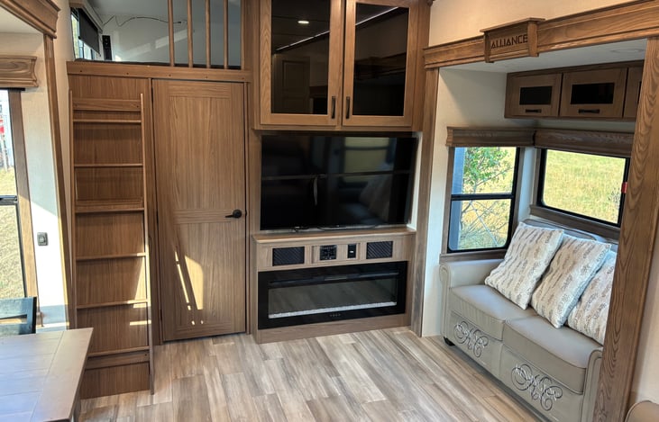 Living room with large flat screen Roku TV, working electric fireplace, lots of windows for natural light, and access to loft bunk