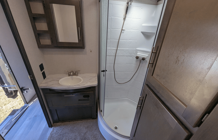Bathroom with storage, and a tall double-glass shower.