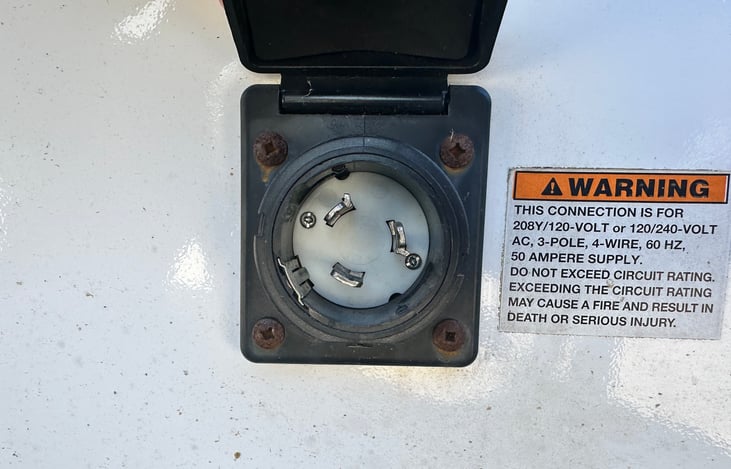 50 amp shore power connection for campground hookups. Secure and weather-protected electrical access point.