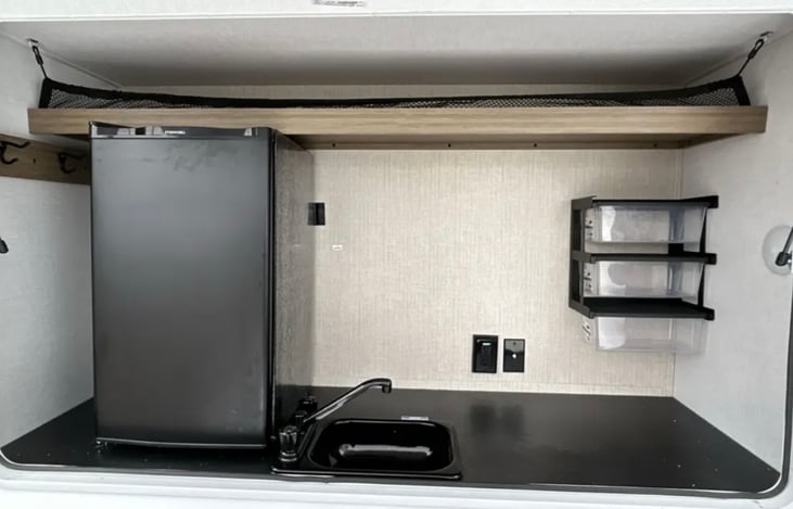 Outdoor kitchen with sink, refrigerator, gas grill and Blackstone griddle.