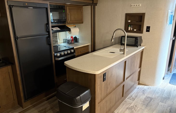 Kitchen with fridge, microwave, stove/oven, toaster oven and coffee pot.