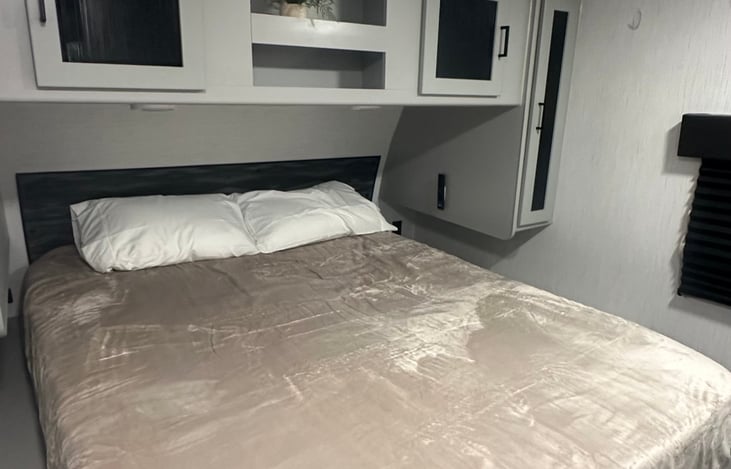 Queen bedroom with sliding door for privacy. Hanging closets on both sides, storage above bed and full closet on opposite wall.