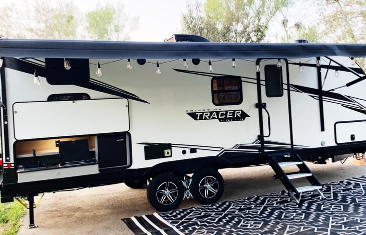 Trailer includes powered awning, large outdoor rug and outdoor lights for a beautiful evening ambiance.