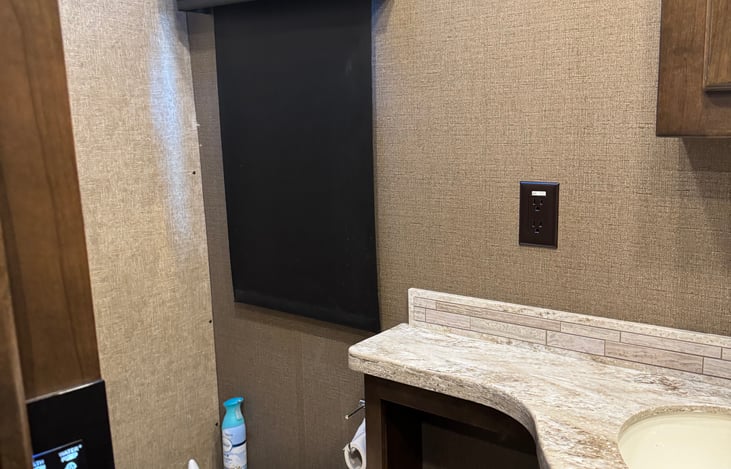 half bath off living area includes medicine cabinet, 2 mirrors, sink, toilet, small storage areas under sink