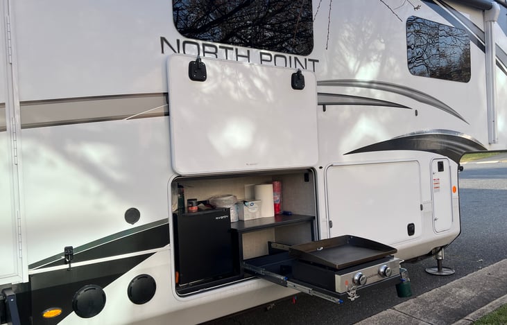Outdoor kitchen area with 22” Blackstone and mini fridge