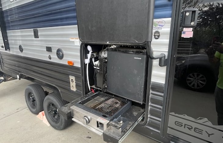 Outdoor kitchen with grill, fridge and ice maker.