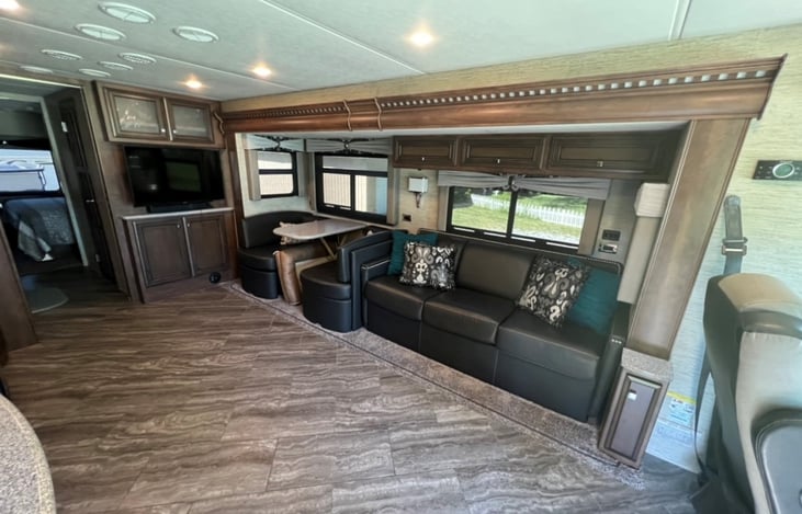 Spacious living room with 2 TVs, sofa bed, and dinette that turns into a small bed.