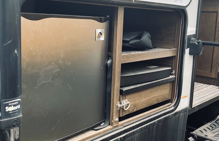 Outdoor kitchen with mini fridge and cooktop.