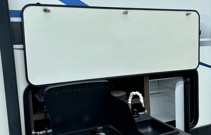 Outdoor Kitchen with stove, sink, and refrigerator. Great for keeping drinks at easy access, cooking fish (which is not aloud in the rv), and hanging outside with friends and family.