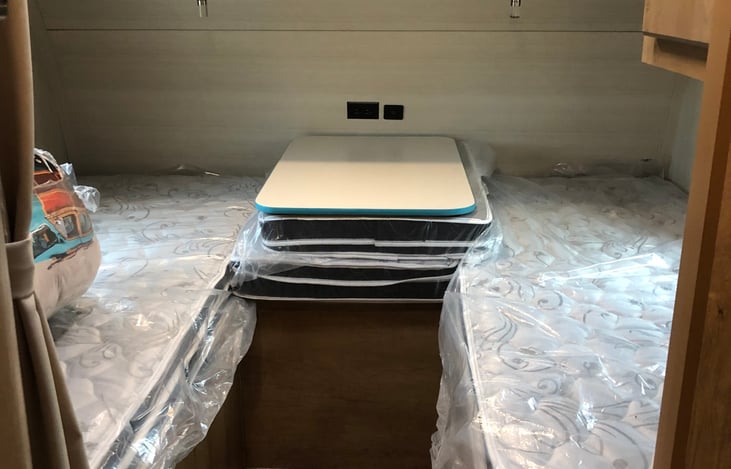 Bedroom is in the front of the trailer with windows on right and left